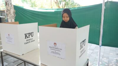 Seorang warga melakukan simulasi menggunakan hak pilihnya dengan mencoblos surat suara di bilik suara. (jogjakota.go.id)